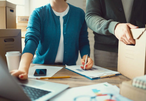 Person creating a moving checklist next to packing boxes