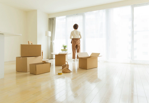 A person standing i an empty room filled with cardboard boxes