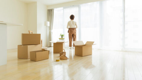 A person standing i an empty room filled with cardboard boxes