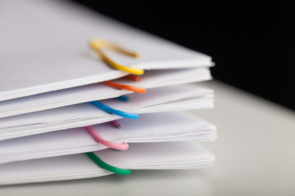 A stack of documentation separated by colorful paper clips