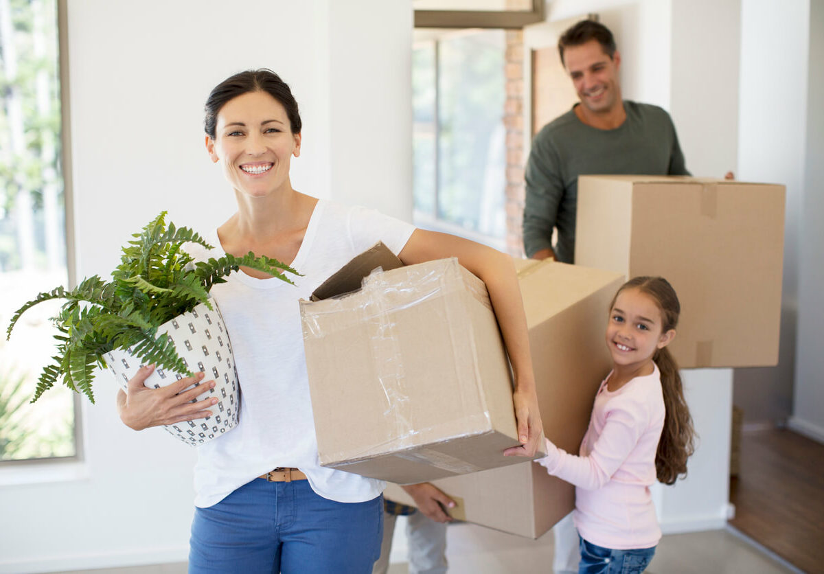 A family carrying boxes into a house