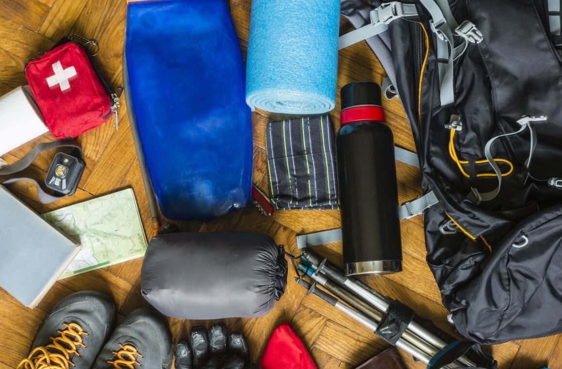 Camping equipment scattered across wooden floor