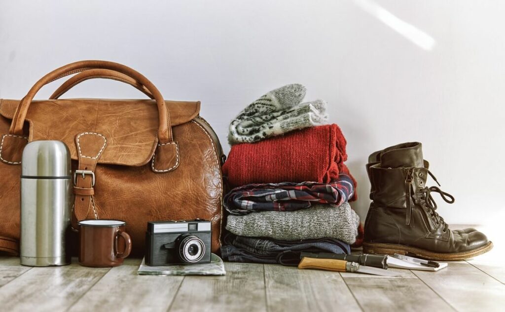 Camping gear like clothes and a camera laid out on the floor.