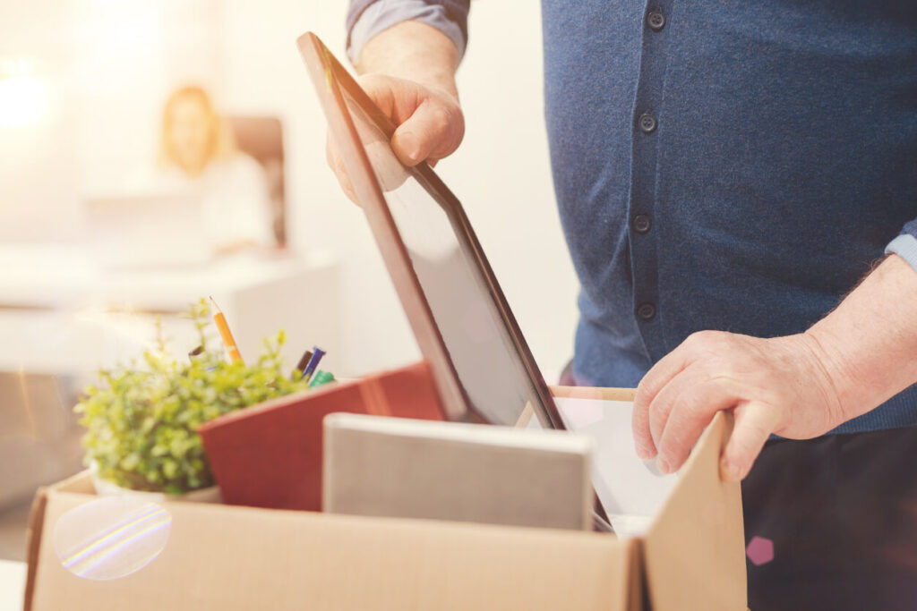 A person packing items into a cardboard box.