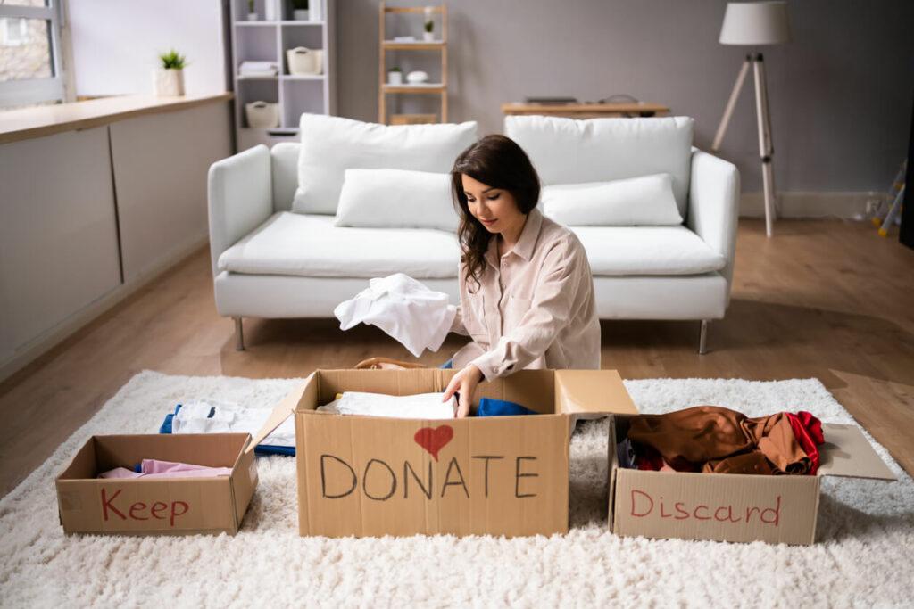 Woman sorting items into boxes and deciding whether to keep, donate, or discard them.