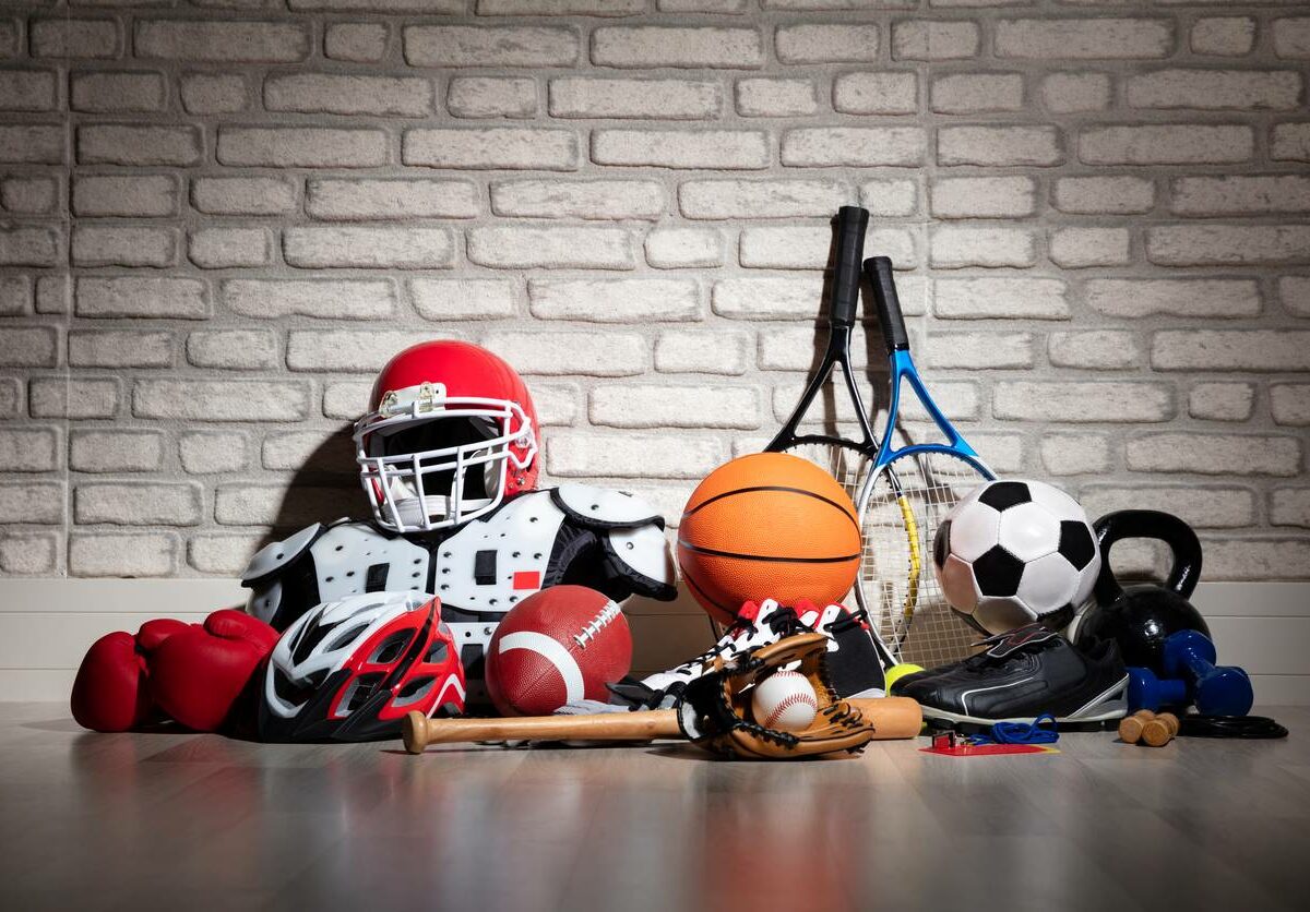 Sports equipment laid out on a floor in front of a white brick wall.