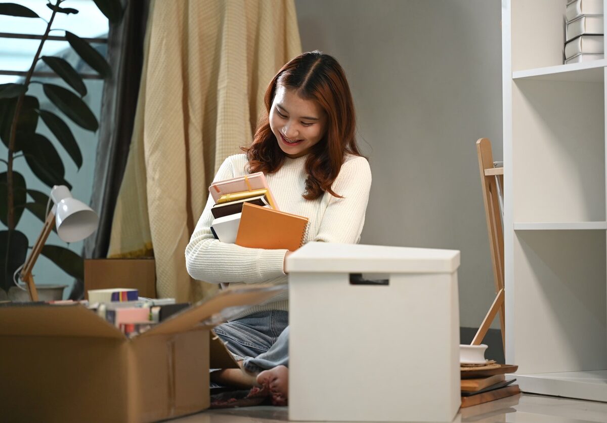 A young female student rearranges books in her dorm for the school year.