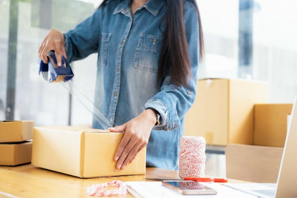 A young female student tapes up boxes for self storage.