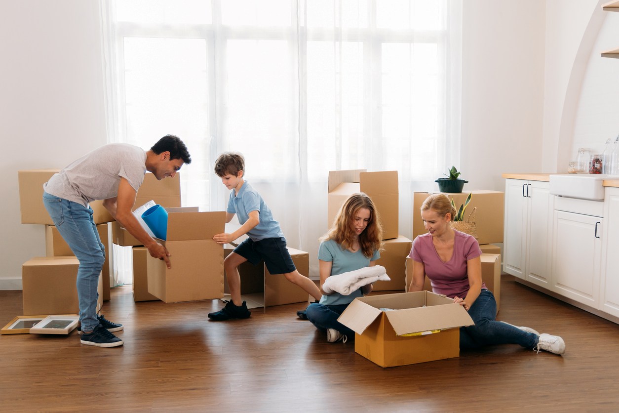 A family packing boxes together in a kitchen and living area.